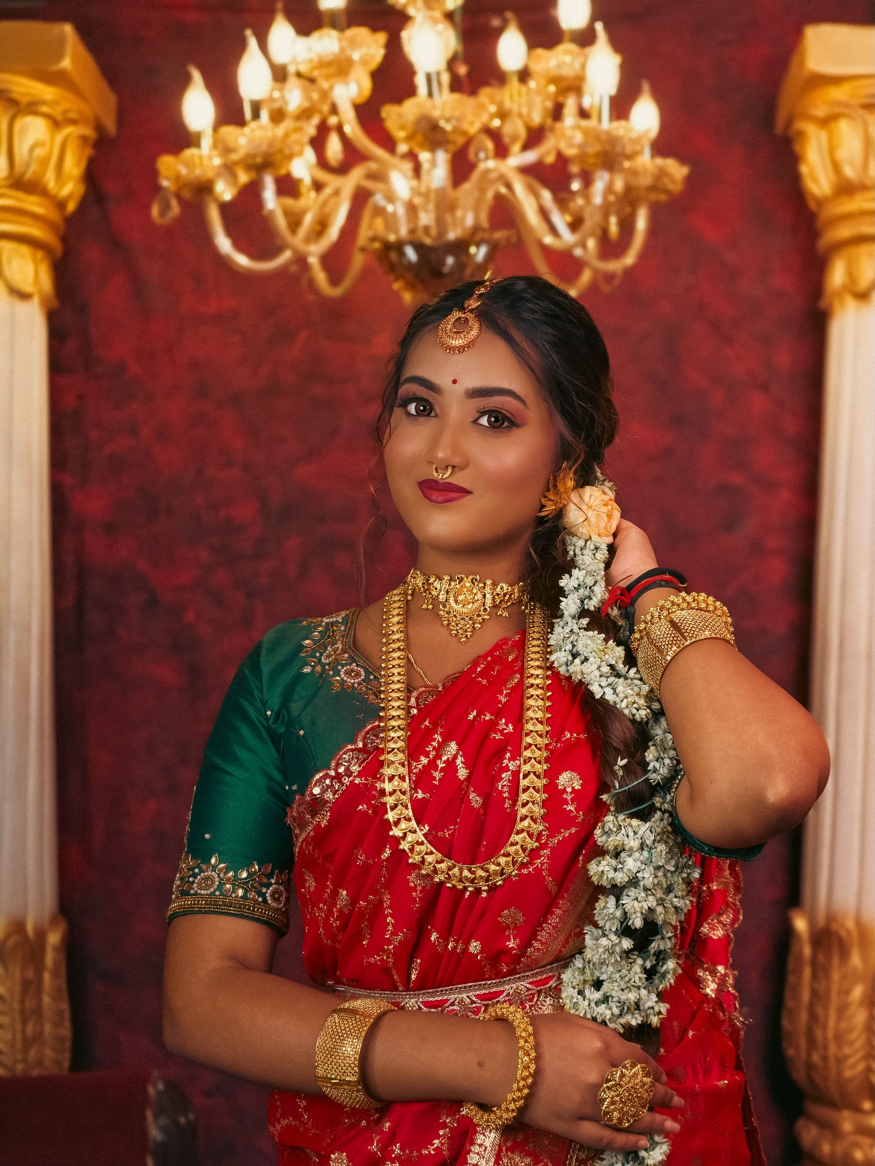 Bride in temple gold collection beneath a chandelier