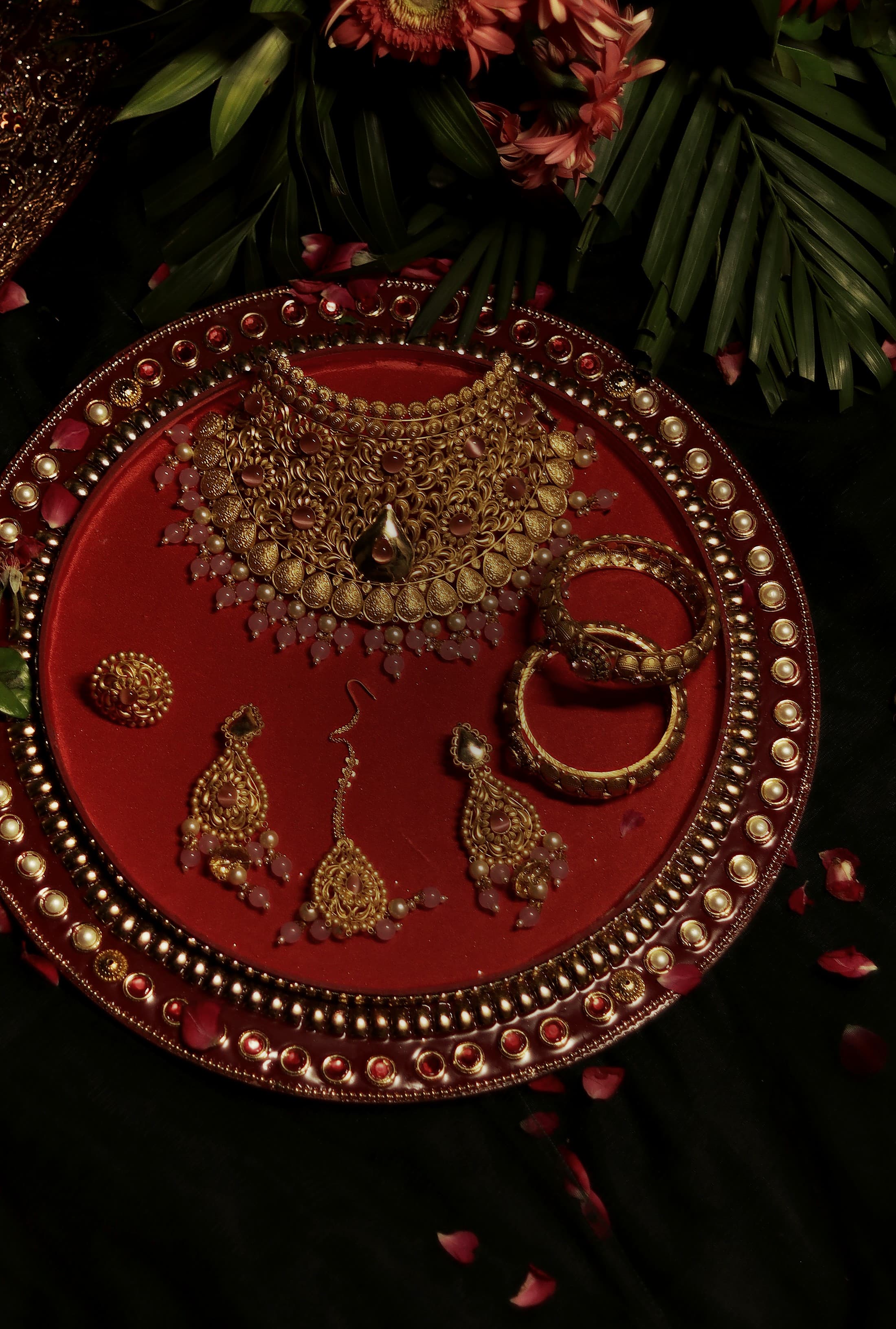 New arrival gold bridal jewellery set on an ornate platter with fresh flowers